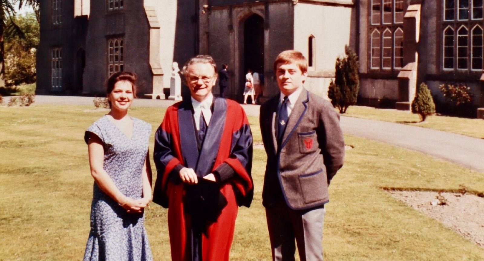 A Warden in scarlet gown with pupils on the front lawn, from the College archives