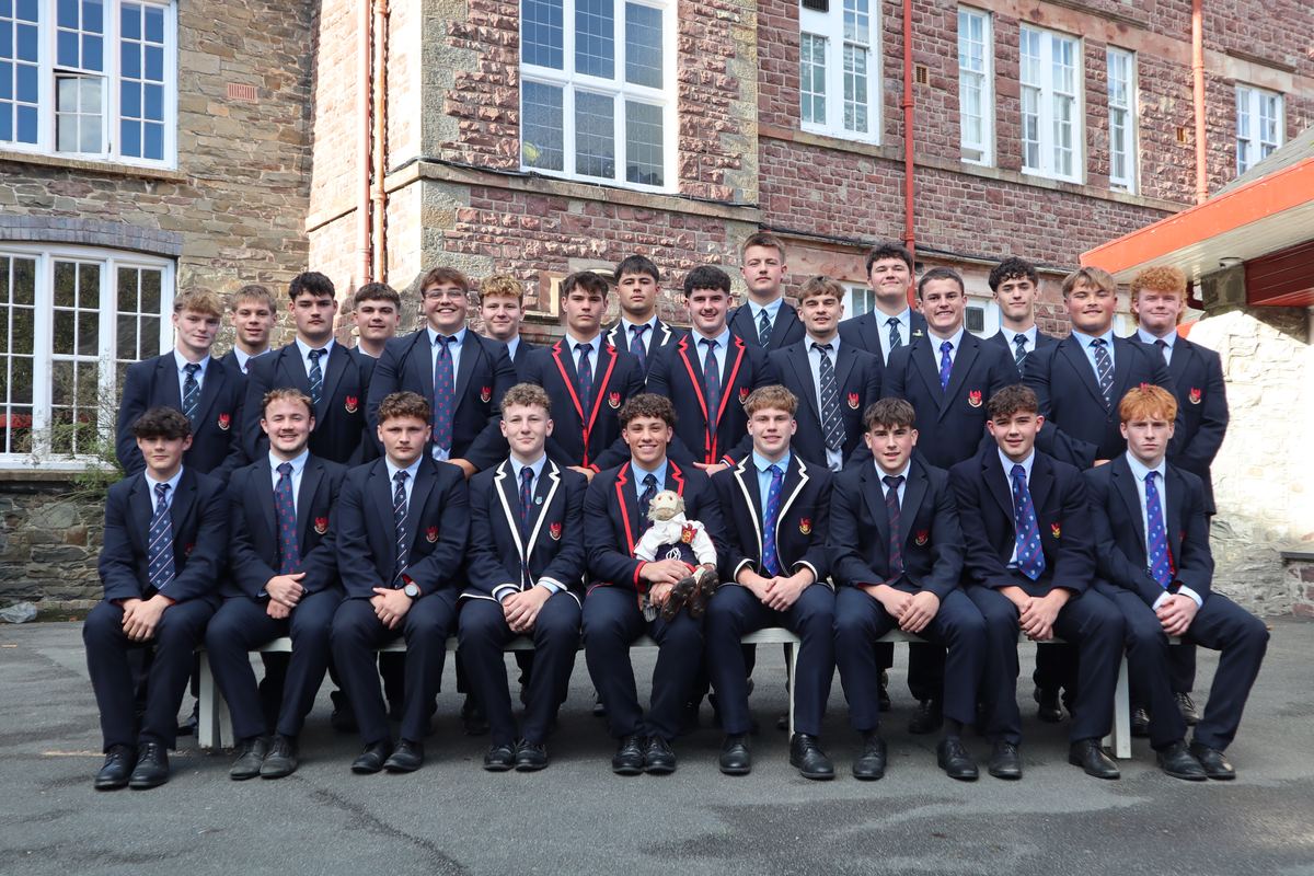 The 1st XV in College blazers in two rows, the captain at the centre holding the College Monkey