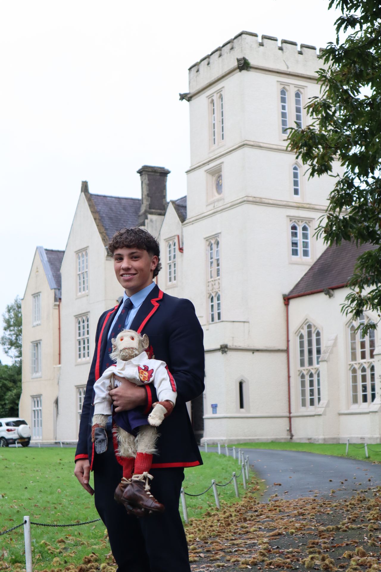 Cole, Captain of the 1st XV, holding the College Monkey in front of the main College building