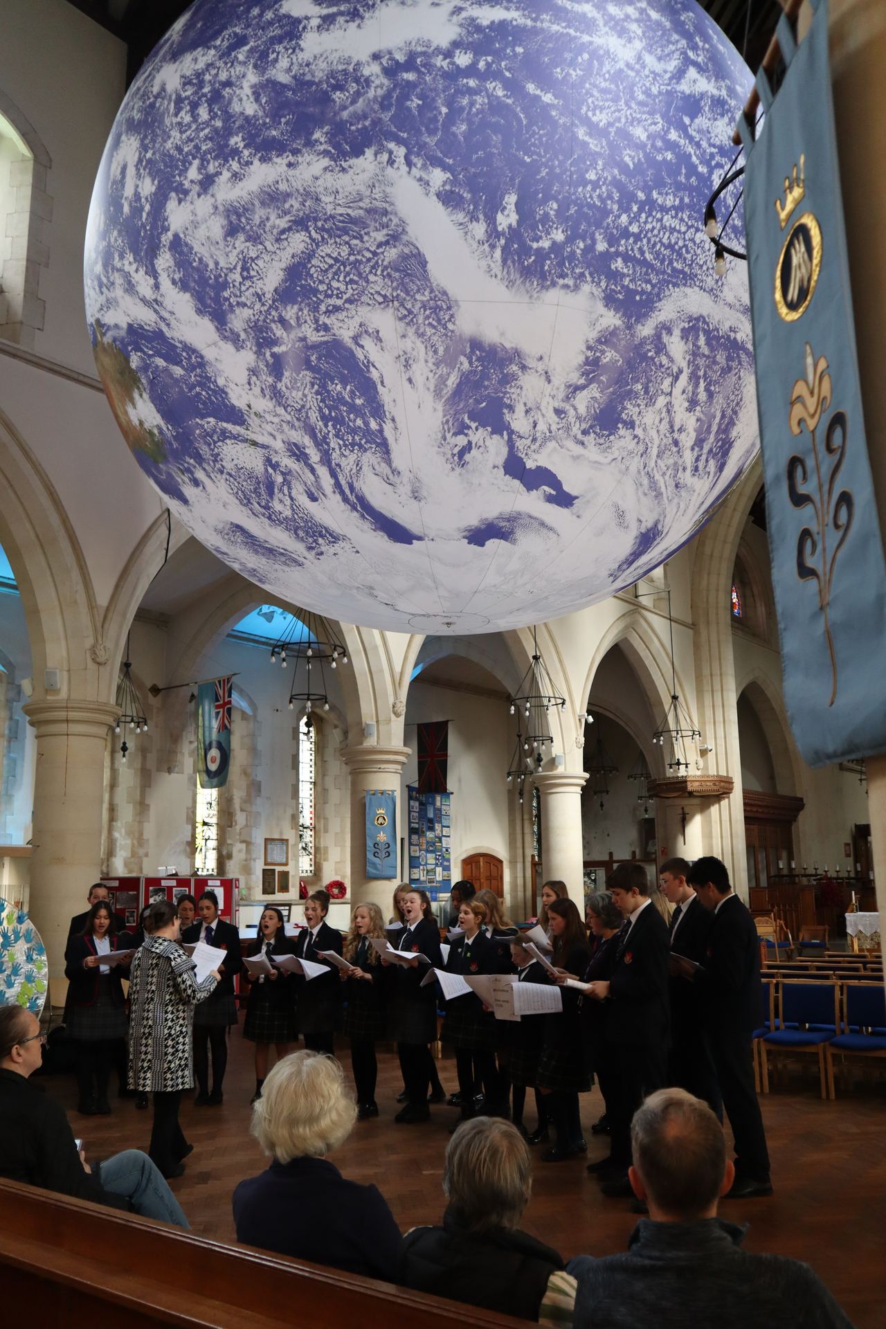 The College Chamber Choir singing in St Mary's Church, Swansea, beneath Luke Jerram's suspended artwork of the Earth, Gaia