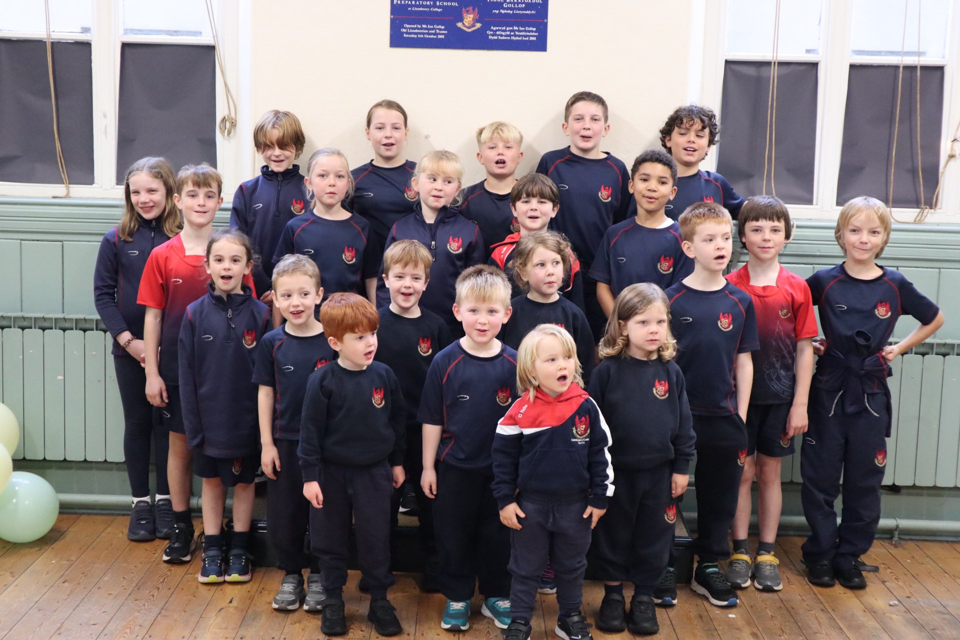 Gollop Prep School pupils in sports kit beneath the plaque marking the School's opening in 2001